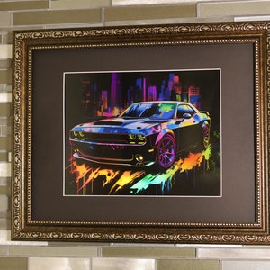 Puede incluir: Impresión artística enmarcada que presenta una ilustración estilizada de un coche deportivo negro con acentos coloridos. La obra de arte representa el coche frente a un paisaje urbano con colores neón vibrantes. El marco es ornamentado con un acabado dorado.