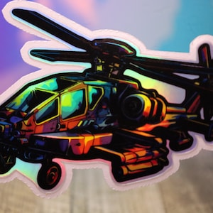 May include: A holographic sticker featuring a stylized illustration of a helicopter. The artwork uses a vibrant color palette of orange, yellow, green, and blue. The sticker has a white border and a glossy finish.