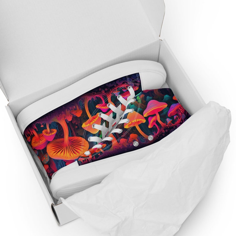 May include: High-top canvas trainers with a vibrant, psychedelic mushroom design. The shoes have a white sole and laces, and are in a white box. The colourful pattern includes orange, pink, and purple mushrooms.