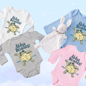 Pu&ograve; includere: Quattro body per bambini bianchi, grigi, blu e rosa, ciascuno con maniche lunghe. I body presentano una tartaruga dei cartoni animati con occhiali da sole con la scritta "Aloha Beaches!" in blu.