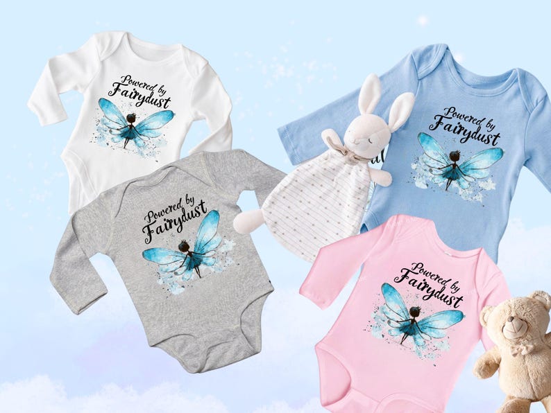 Puede incluir: Cuatro bodies de beb&eacute; en blanco, gris, azul y rosa, cada uno con un dise&ntilde;o de manga larga. El texto "Powered by Fairydust" est&aacute; impreso sobre una ilustraci&oacute;n de hada con alas azules. Un conejito de peluche y un osito de peluche tambi&eacute;n est&aacute;n en la imagen.