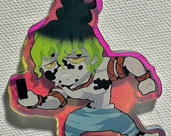 Puede incluir: Un personaje de anime verde y negro con un teléfono en una mano, de pie sobre un fondo rosa y naranja. El personaje tiene un patrón blanco y negro en su cuerpo y lleva un atuendo azul y blanco. El personaje es un llavero.
