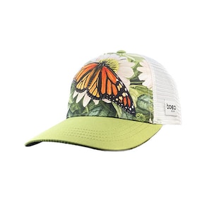 May include: A green and white trucker hat with a butterfly and floral print. The hat has a mesh back and a "BOBO" logo on the side.