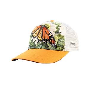 May include: A white and orange butterfly trucker hat with a green floral print. The hat has a mesh back and a yellow brim.