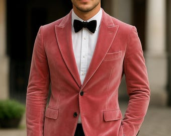May include: A dusty rose velvet blazer with a black bow tie and black pants. The blazer has a two-button closure and a notched lapel. The outfit is completed with a white dress shirt.