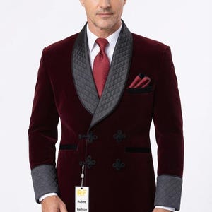 May include: A deep burgundy velvet smoking jacket featuring a black quilted shawl collar and matching quilted cuffs. The jacket has a double-breasted front with black frog closures, a white dress shirt, a red tie, and a pocket square. A tag reads RF Rubee Fashion.
