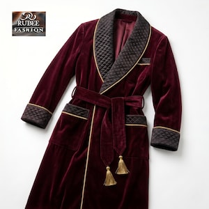 May include: A burgundy velvet robe with a quilted black collar and cuffs, trimmed with gold piping. The robe features a matching belt with tassels and pockets. The Rubee Fashion logo is in the upper left corner.