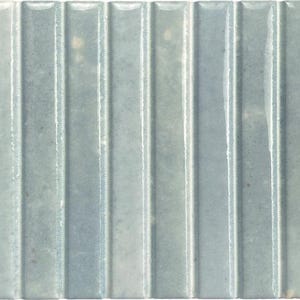 May include: A rectangular ceramic tile featuring a glossy, light blue-grey finish with a series of vertical, raised ridges running across the surface. The glaze has subtle variations in tone and small, light-colored speckles throughout.