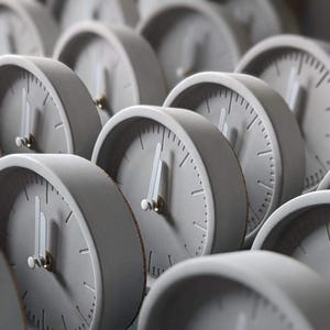 Puede incluir: Una colección de relojes de hormigón gris con manecillas blancas y marcas negras. Los relojes están dispuestos en un patrón escalonado, creando una pantalla visualmente atractiva.