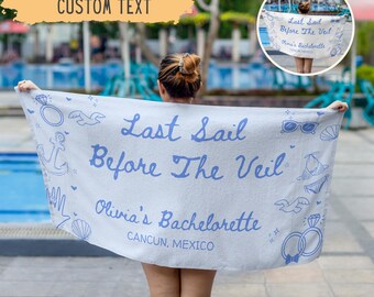 May include: A white beach towel with blue text that reads "Last Sail Before The Veil" and "Olivia's Bachelorette, Cancun, Mexico." The towel has nautical-themed illustrations.