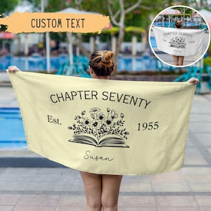 May include: A yellow beach towel with black text that reads "Chapter Seventy Est. 1955" and a floral design with an open book. The name "Susan" is written in cursive below the book.