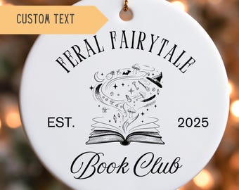 May include: White ceramic ornament with gold string, featuring the text "FERAL FAIRY TALE BOOK CLUB" and a whimsical illustration of a book with magical elements. Includes the text "EST. 2025" and "CUSTOM TEXT".