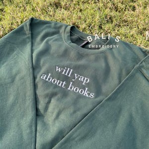 May include: A dark green sweatshirt with the text "will yap about books" embroidered in white on the front.