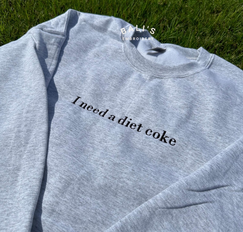 May include: Gray sweatshirt with black embroidered text that reads "I need a diet coke".