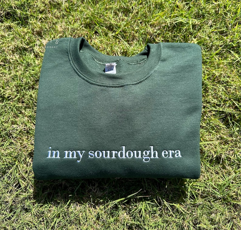 May include: A dark green sweatshirt with the text "in my sourdough era" embroidered in white on the front.