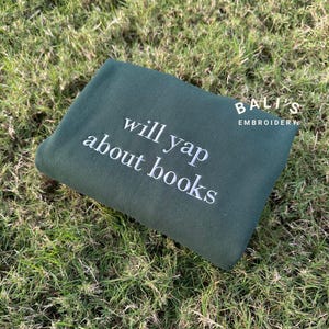 May include: A dark green sweatshirt with the text "will yap about books" embroidered in white.