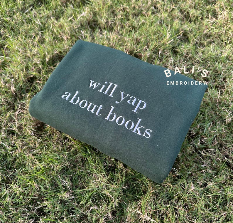 May include: A dark green sweatshirt with the text "will yap about books" embroidered in white.
