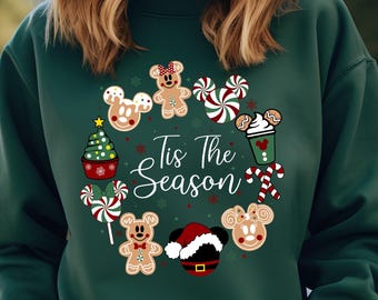 May include: Green Christmas sweatshirt with a festive design featuring Mickey Mouse and Minnie Mouse characters, gingerbread cookies, candy canes, and a Christmas tree. The text "Tis The Season" is printed on the front.
