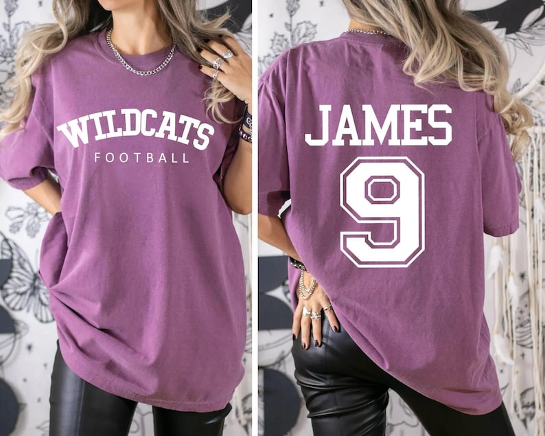 May include: Purple oversized t-shirt with white text that says "Wildcats Football" on the front and "JAMES 9" on the back.