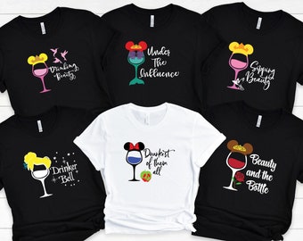 Op de afbeelding: Zes zwart-witte t-shirts met een Disney-prinsessthema en wijnglasafbeeldingen. De shirts bevatten de tekst "Drinking Beauty", "Under The Influence", "Sipping Beauty", "Drinker Bell", "Drunkest of them all" en "Beauty and the Bottle".