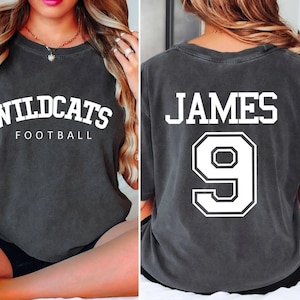May include: Two gray t-shirts with white text. The first shirt says "Wildcats Football" and the second shirt says "James 9".