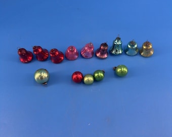 May include: A collection of small vintage glass ornaments consisting of nine bell-shaped pieces in red, pink, purple, blue, and gold, alongside four spherical ornaments in light green and red, each featuring a small metal loop for hanging purposes.