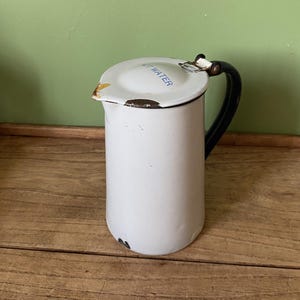 May include: White enamel jug with a black handle and a blue and white "Cold Water" label on the lid.