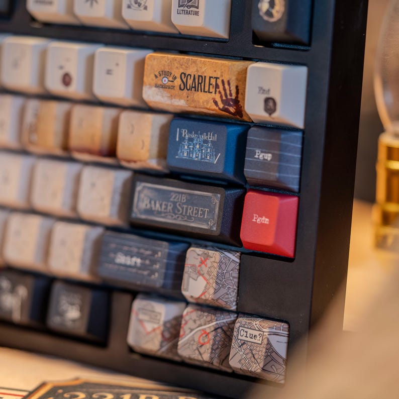 May include: Close-up of a black mechanical keyboard with custom keycaps. Keycaps feature text and graphics, including "Study in Scarlet," "221B Baker Street," and map designs. The keyboard has a variety of colors and textures.