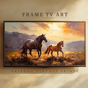 Könnte beinhalten: Gerahmter digitaler Kunstdruck mit zwei Pferden in einer Landschaft. Das Kunstwerk zeigt ein dunkelbraunes Pferd und ein hellbraunes Pferd, die über ein Feld mit Bergen im Hintergrund gehen. Der Himmel ist eine Mischung aus Orange und Gelb.