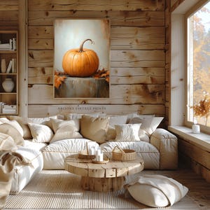 May include: A painting of a single orange pumpkin with fall leaves on a stone surface. The painting is framed and hanging on a wooden wall in a living room setting.