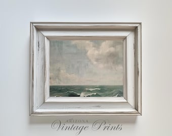 May include: A framed landscape painting depicting a seascape with dark green waves under a pale, cloudy sky. The artwork is enclosed in a wide, distressed white wooden frame with a weathered finish. The text Arizona Vintage Prints is visible.