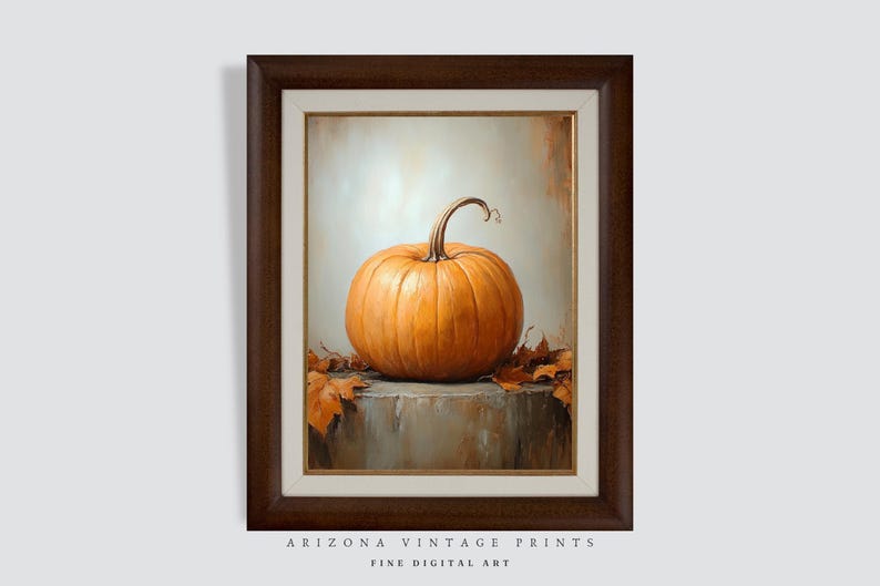 May include: A framed painting of a single orange pumpkin with a stem, sitting on a textured surface with brown leaves. The background is a light beige color.