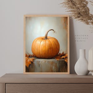 May include: A painting of a single orange pumpkin on a gray surface with brown leaves. The pumpkin has a brown stem and is sitting on a table. The background is a light gray color.