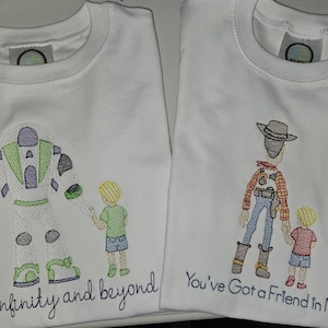 Puede incluir: Dos camisetas blancas con diseños bordados. La camiseta de la izquierda muestra a un personaje de guardián espacial de la mano de un niño con el texto to infinity and beyond. La de la derecha muestra a un vaquero de la mano de un niño con el texto You've Got a Friend in Me.