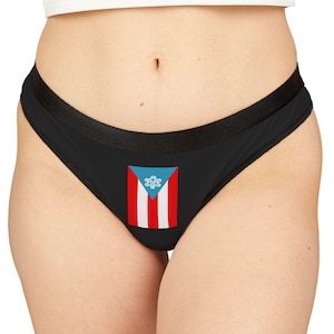 May include: Black thong underwear featuring the Puerto Rican flag. The flag design includes a white star on a blue background, with red and white stripes. The underwear has a black waistband and trim.