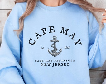 May include: Light blue sweatshirt with a black graphic of an anchor and the text "CAPE MAY Est. 1848 CAPE MAY PENINSULA NEW JERSEY".