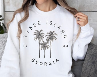 May include: White sweatshirt with a black graphic print of palm trees and the text "Tybee Island 17 33 Georgia".