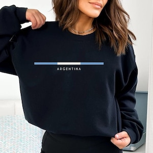 May include: Black sweatshirt with a blue and white stripe across the chest and the word "ARGENTINA" printed below the stripe.