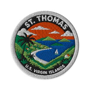 May include: A circular embroidered patch featuring a tropical landscape with green hills, a blue bay, a white sailboat, and an orange sky. The text ST. THOMAS is arched at the top and U.S. VIRGIN ISLANDS is arched at the bottom in white letters.