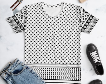 Könnte beinhalten: Ein kurzärmeliges T-Shirt mit V-Ausschnitt und schwarz-weißem Keffiyeh-Muster. Der Hauptteil zeigt ein sich wiederholendes Rautenmuster, während die Ärmel und der untere Saum mit markanten geometrischen Blumen- und Zickzackmustern verziert sind.