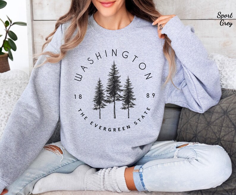 May include: A gray sweatshirt with a black graphic design featuring the words "WASHINGTON THE EVERGREEN STATE" and the numbers "1889" around a circle with three pine trees inside.