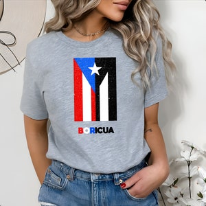 May include: Gray t-shirt with a distressed image of the Puerto Rican flag and the word "BORICUA" printed below it.