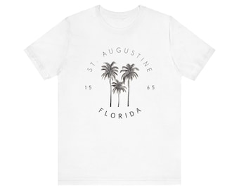 Może przedstawiać: Biała koszulka z czarno-białym nadrukiem graficznym palm i tekstem "ST. AUGUSTINE 15 65 FLORIDA"
