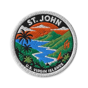 May include: A circular embroidered patch featuring a tropical landscape with a blue bay, green hills, and palm trees under an orange sunset sky. The text ST. JOHN is arched at the top and U.S. VIRGIN ISLANDS is arched at the bottom in white letters.