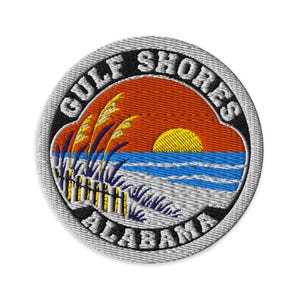 Puede incluir: Un parche bordado circular que muestra una escena de playa con un sol amarillo, cielo naranja, océano azul y dunas de arena blanca con hierba alta. El texto negro del borde dice GULF SHORES en la parte superior y ALABAMA en la parte inferior.