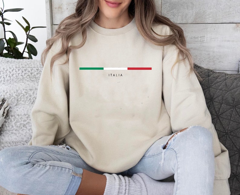 May include: A beige sweatshirt with a horizontal stripe of the Italian flag colors, green, white, and red, and the word "ITALIA" printed below the stripe.