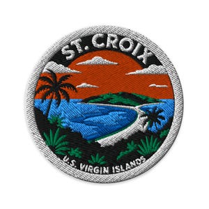 May include: A circular embroidered patch featuring a tropical landscape with a sunset, palm trees, and a blue bay. The text ST. CROIX is arched at the top and U.S. VIRGIN ISLANDS is arched at the bottom in white lettering against a black background.
