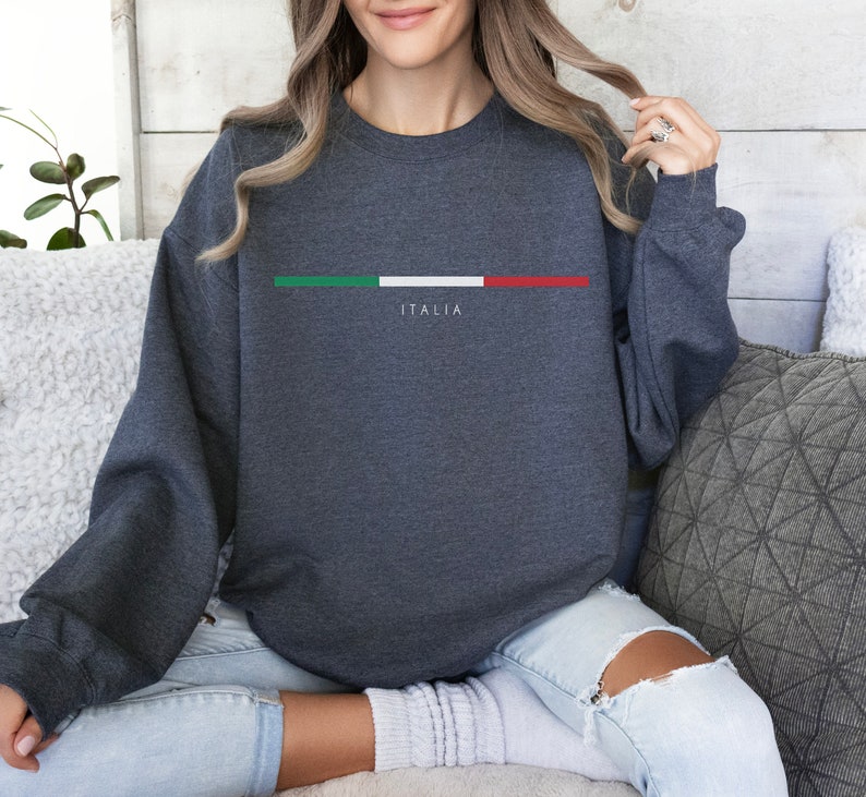 May include: A dark gray sweatshirt with a white stripe and the Italian flag colors in green, white, and red. The word "ITALIA" is printed in white below the stripe.
