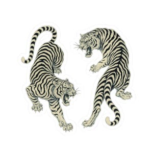 Puede incluir: Dos pegatinas con ilustraciones detalladas de tigres. Los tigres se representan en una pose dinámica, con la boca abierta rugiendo. Los tigres tienen rayas negras sobre un fondo color crema.