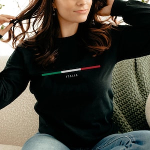 May include: A black long-sleeved shirt with a horizontal stripe of the Italian flag colors, green, white, and red, and the word "ITALIA" printed below the stripe.